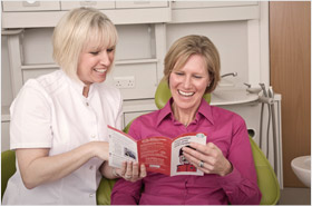 Happy patient looking at leaflets with dentist